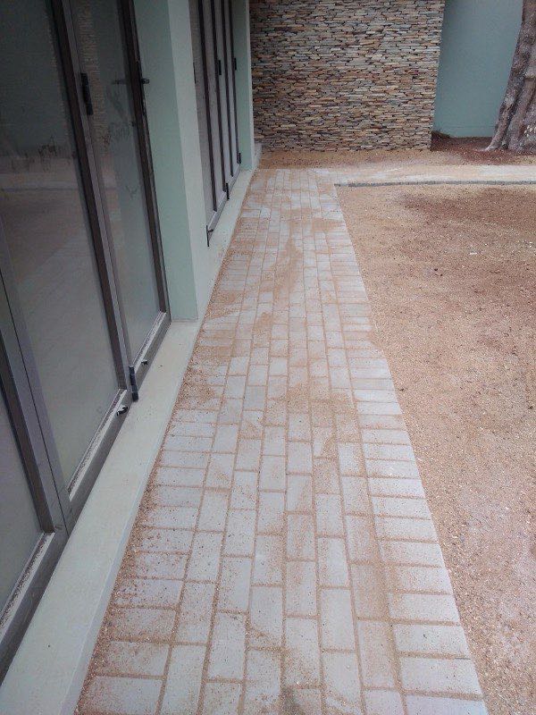 Finished herringbone paver pathway beside stone-clad entrance